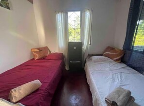 A room with two beds, a window with curtains, a door, and a radiator.