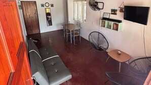 A compact living space with a sofa, dining table, chairs, a TV, and a fan. - House with excellent location in Bagaces Guanacaste (Salitral)