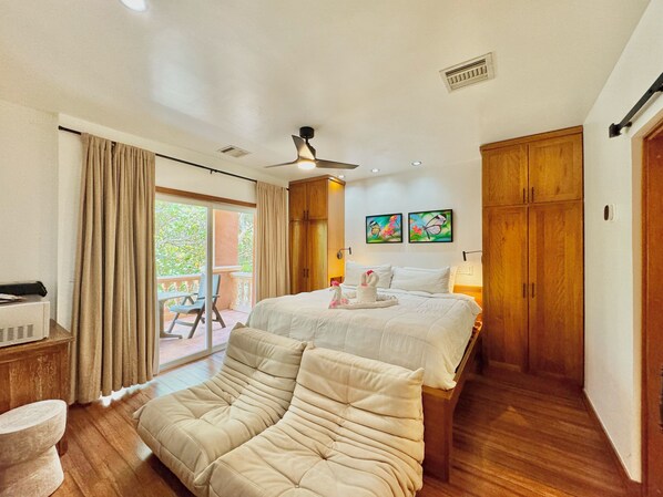 Une chambre avec un lit, un canapé, un ventilateur de plafond et une vue sur l’extérieur.