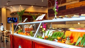 Un espace buffet avec un comptoir en bois, des décorations tropicales et un écran de télévision en arrière-plan.