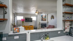 A modern kitchen with a white countertop, grey backsplash, and a ceiling fan.