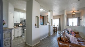 A spacious living area with a brown leather sofa, a kitchen with white cabinets and stainless steel appliances, and a dining area with a table and chairs.