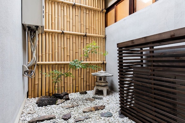 Un jardín japonés tradicional con cerca de bambú, farol de piedra y valla de madera.