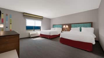 Habitación de hotel con dos camas, un escritorio, una ventana con vistas y una lámpara en el techo.