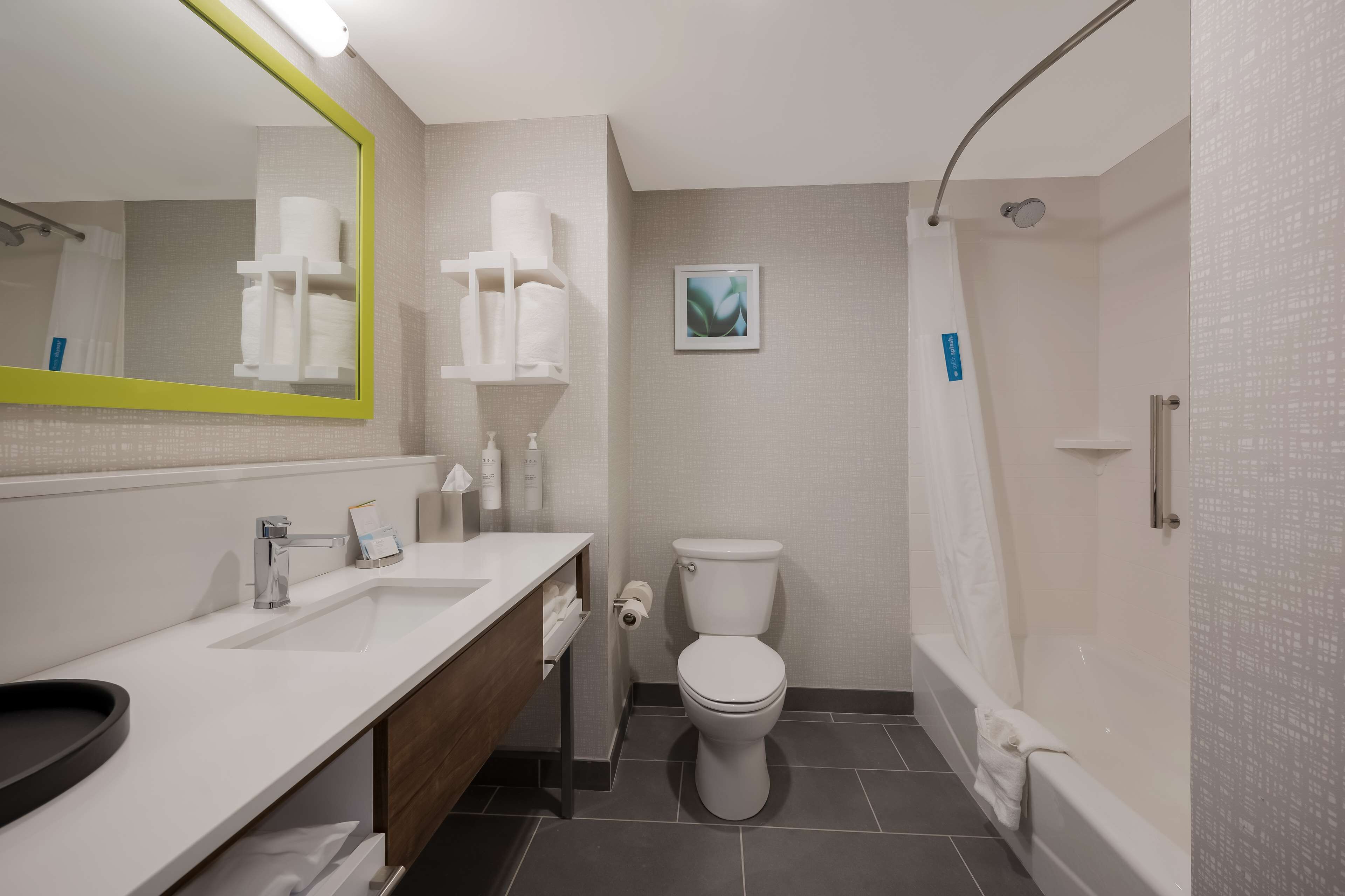 Un baño moderno con lavamanos, espejo, inodoro y ducha blancos.