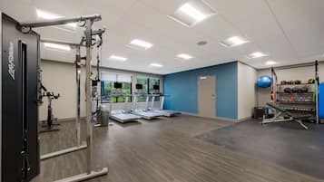 Un gimnasio con cintas de correr, máquinas de pesas y pelotas de ejercicio.
