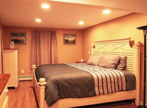 A bedroom with a bed, a nightstand, a lamp, and two paintings on the wall. - 4BR + No Bridge Traffic + Water Wizz Water Park + Pond & Beaches (Bourne)