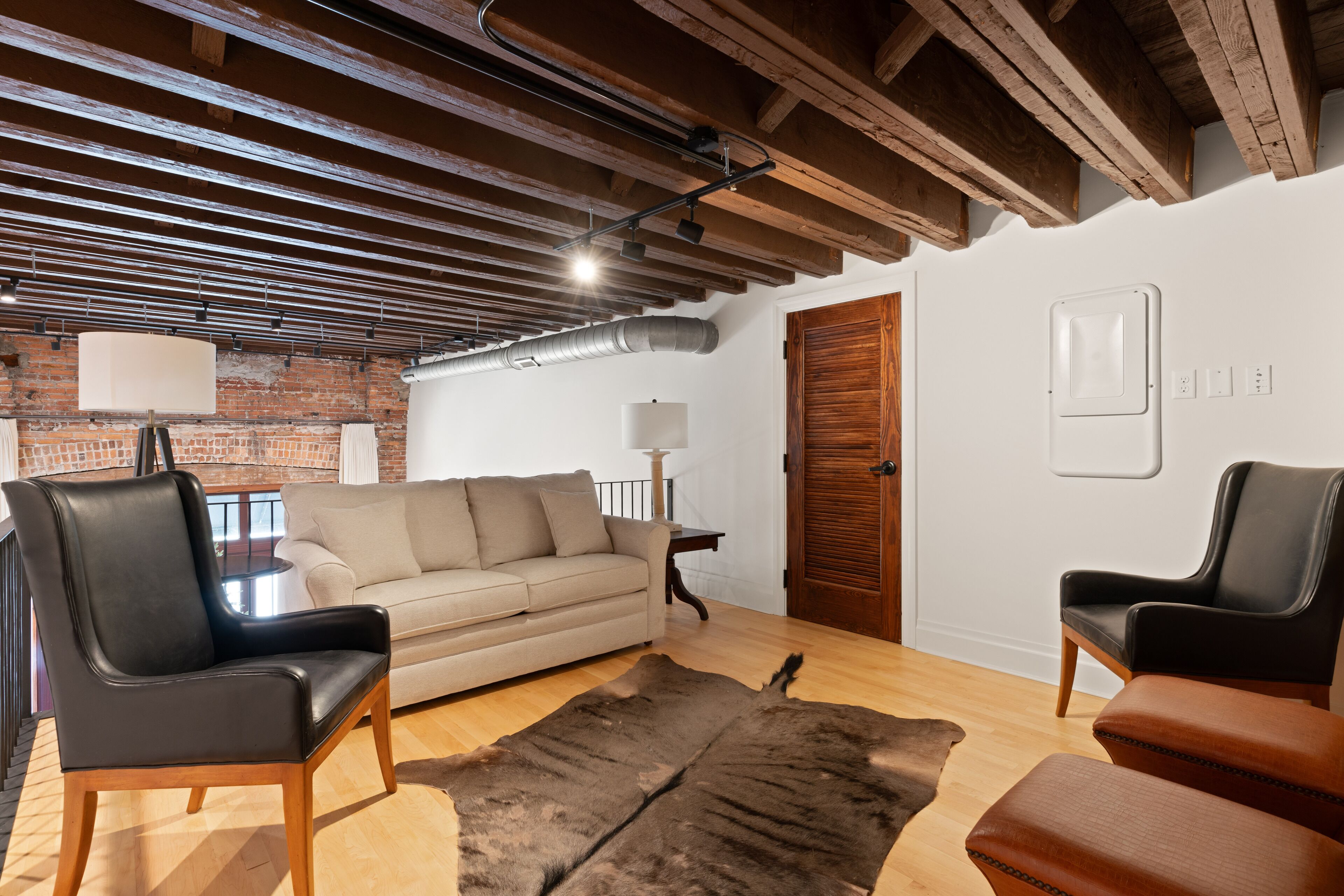 Ein Wohnzimmer mit einer Ledersofa, einem Holztisch und einem Fellteppich.