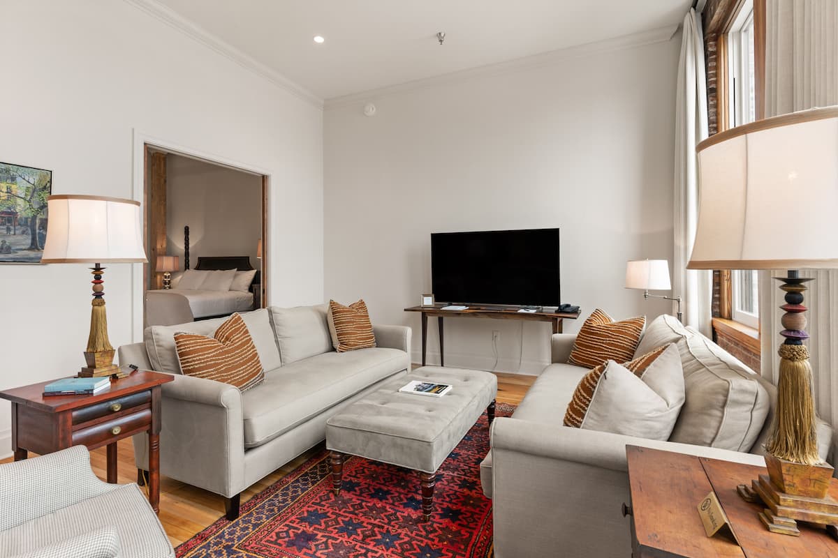 A modern living room with a sofa, ottoman, and a flat-screen TV.