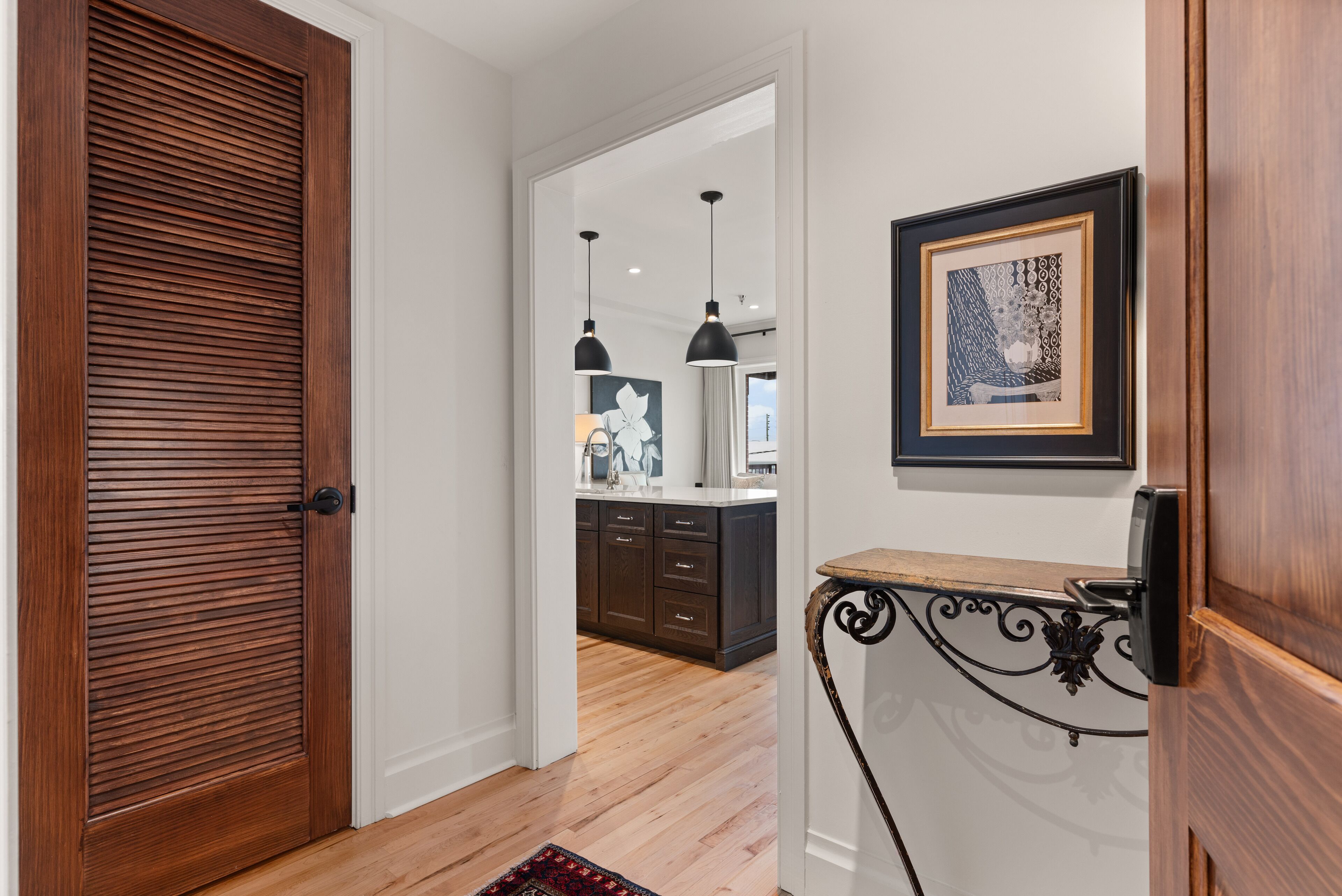 A hallway with a wooden door, a white wall, and a framed artwork.