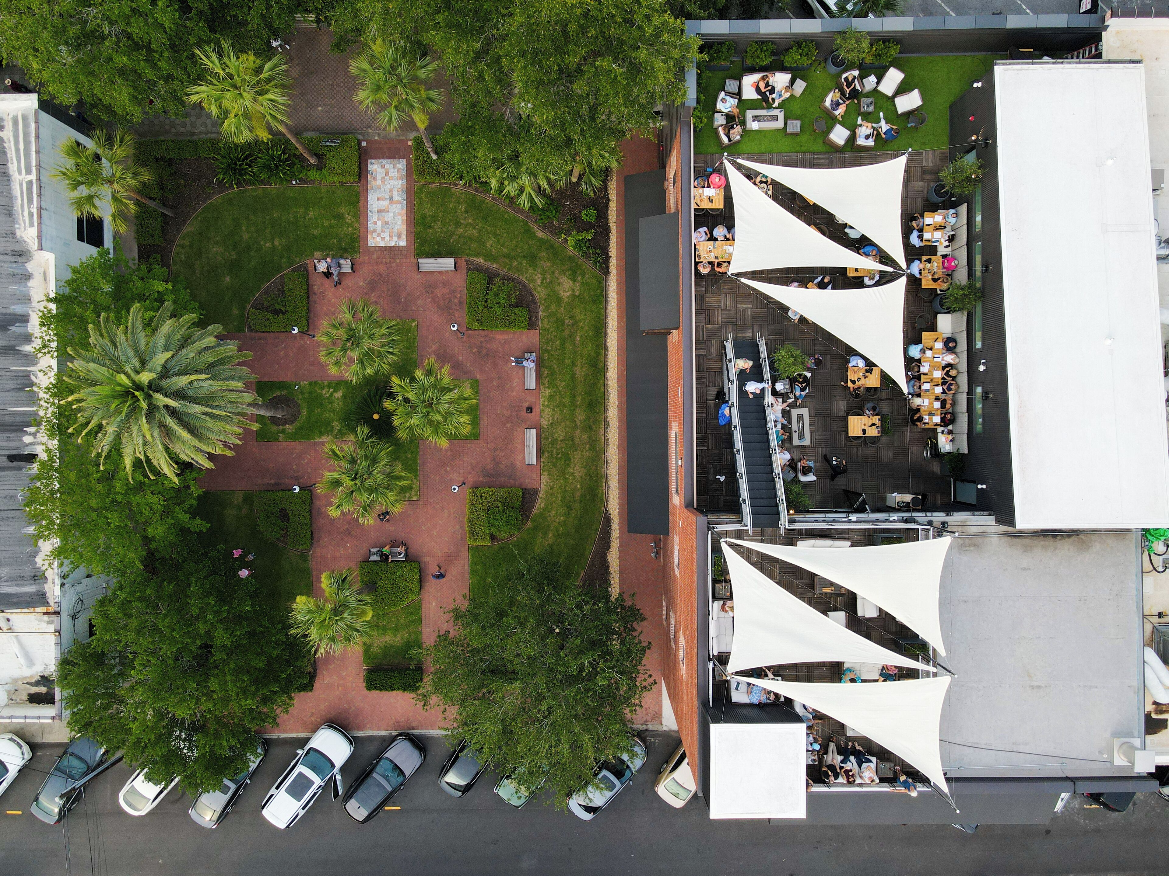 Vista aérea de un patio con jardín central, zonas de estar y aparcamiento.