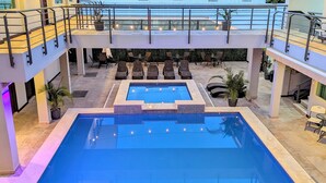 Um hotel moderno com piscina no terraço, vários espaços para relaxar e vista para o horizonte da cidade.