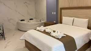 Quarto de hotel com uma cama grande, banheira e cabeceira de madeira.
