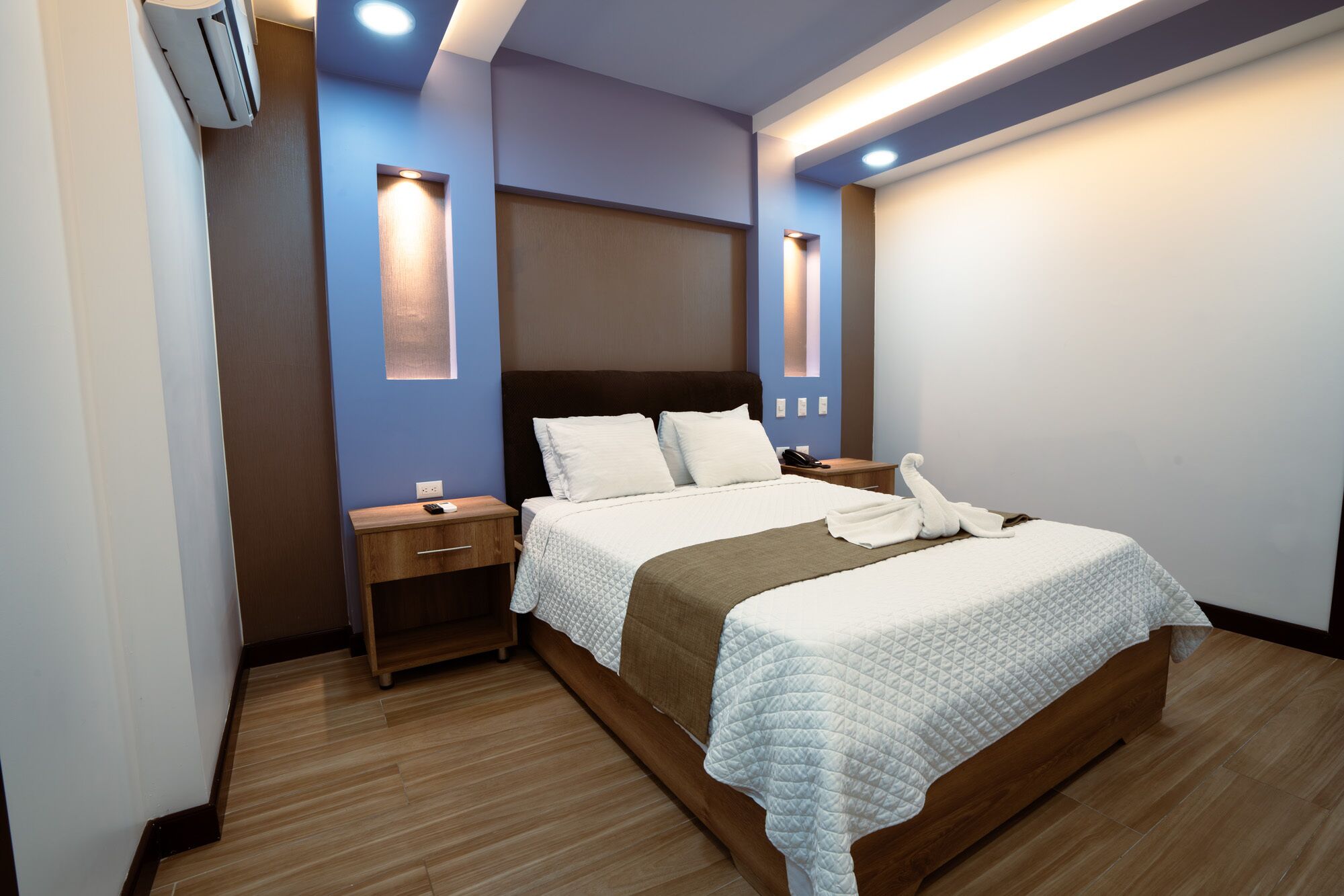 Une chambre d’hôtel moderne dotée d’un grand lit, de tables de chevet et d’un éclairage intégré.