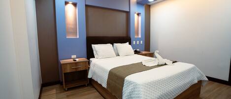 Una habitación de hotel moderna con una cama grande, mesitas de noche e iluminación integrada.