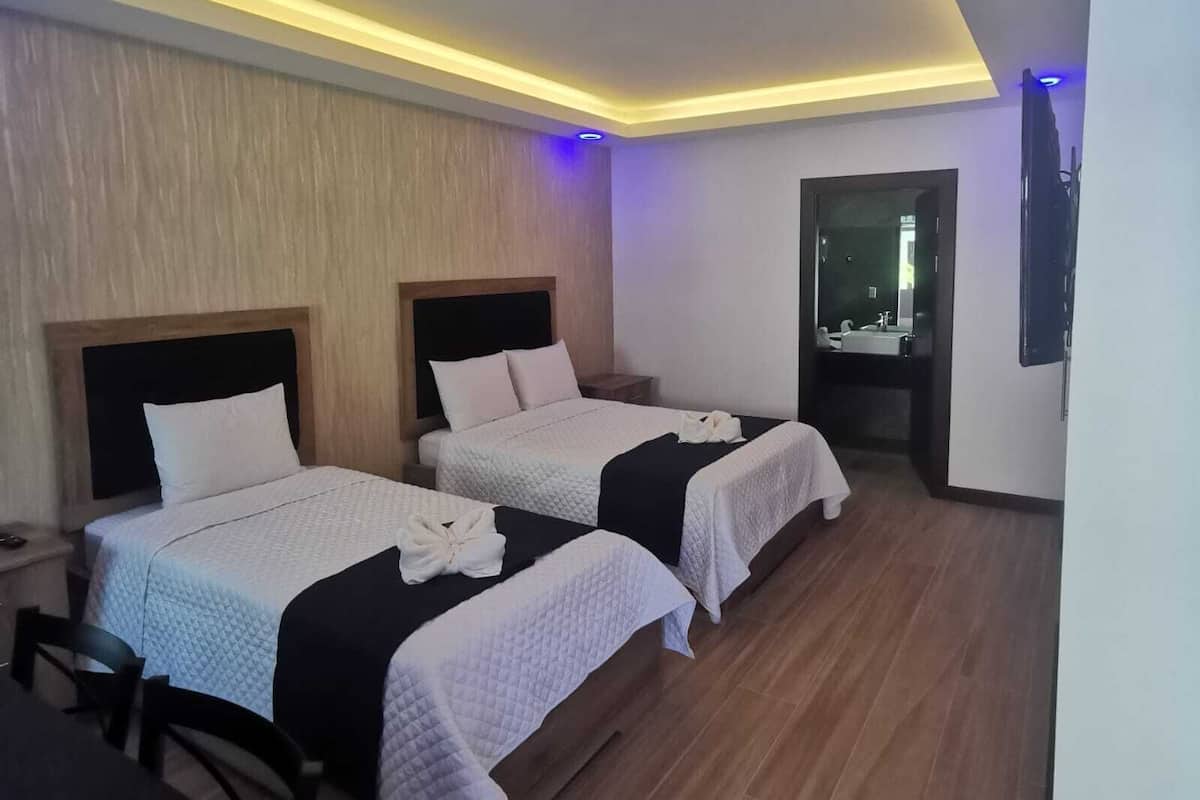 Ein Hotelzimmer mit zwei Betten, einem Schreibtisch und einem Spiegel.