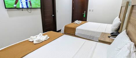 Een hotelkamer met twee bedden, een aan de muur bevestigde televisie en een deur.