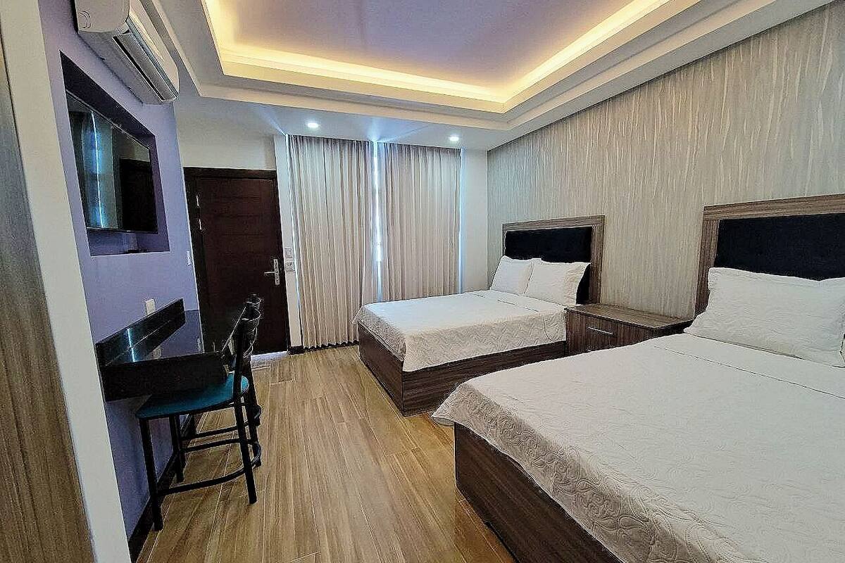 Ein Hotelzimmer mit zwei Betten, einem Schreibtisch und einem Sessel.
