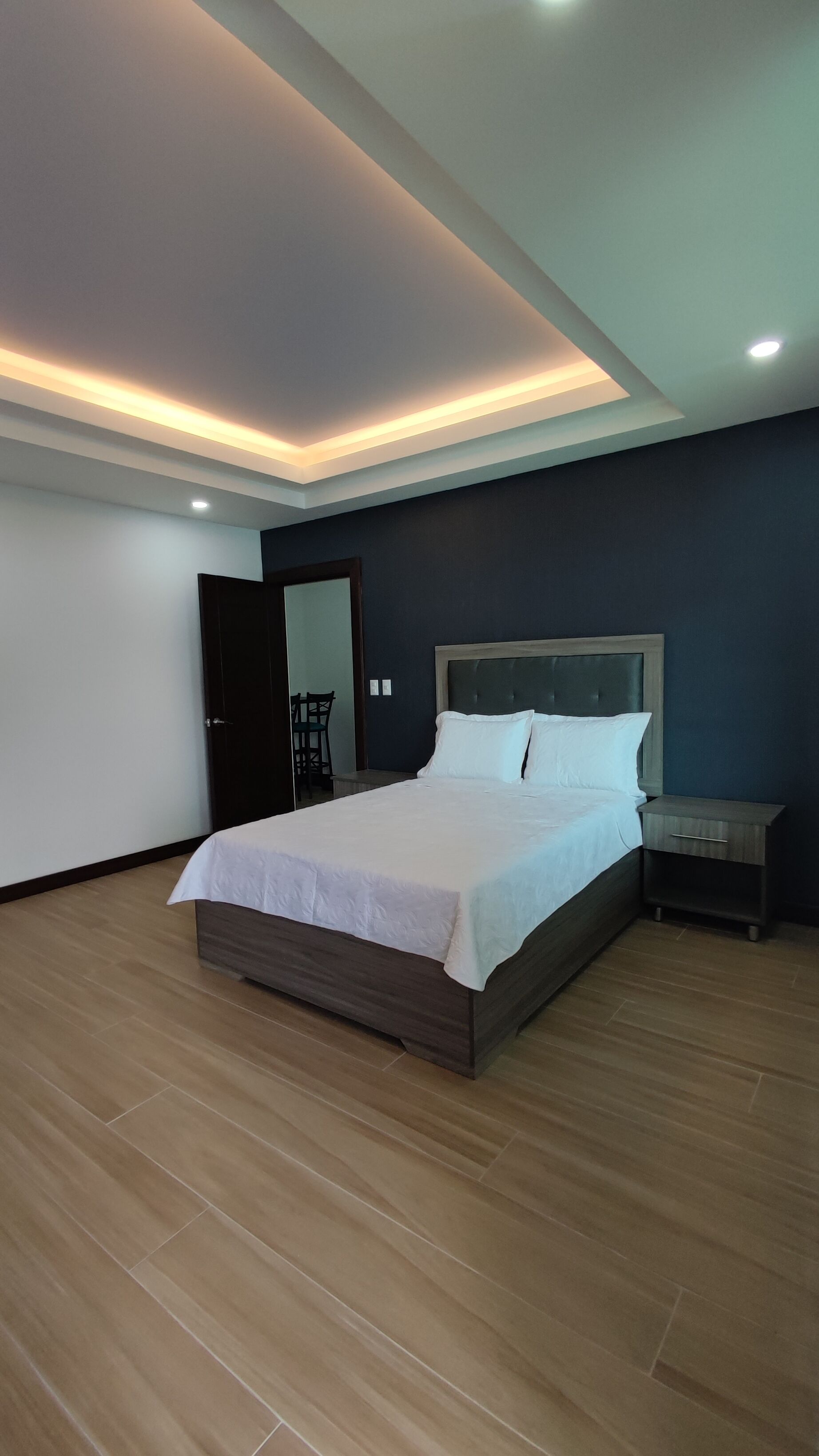Een moderne slaapkamer met een groot bed, een nachtkastje en een stoel.