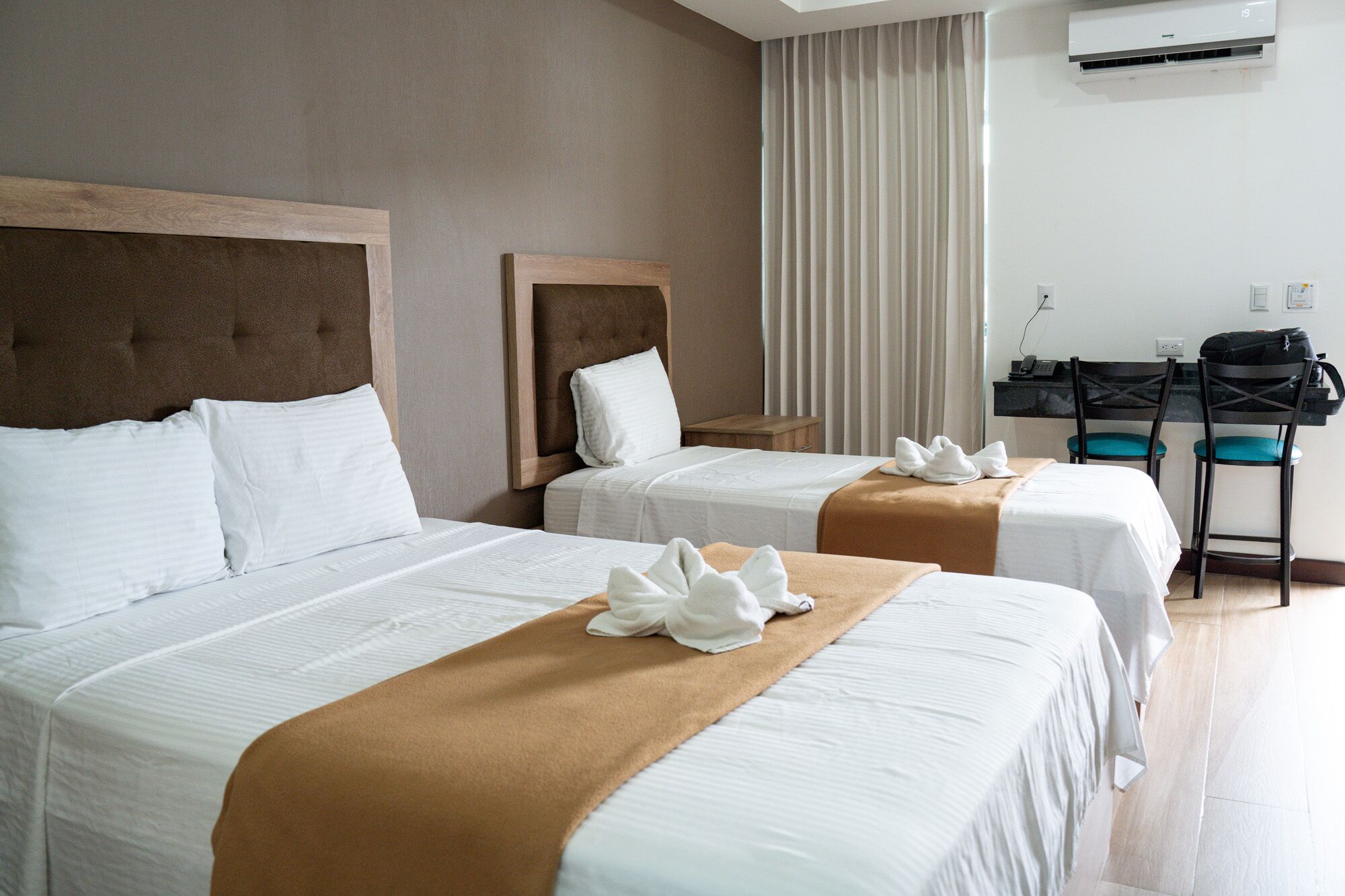 A hotel room with two beds, a desk, and a chair.