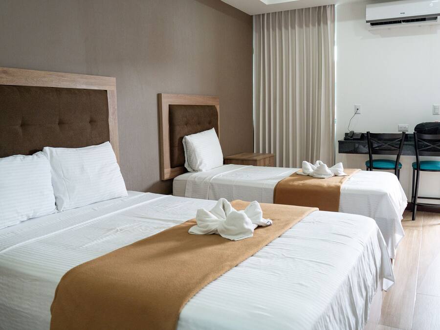 A hotel room with two beds, a desk, and a chair.