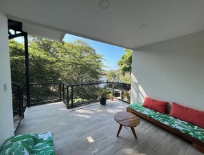 A balcony with a wooden floor, a sofa with red cushions, and a small wooden table. - Unbeatable location.Walking distance to everything! (Puntarenas Province)