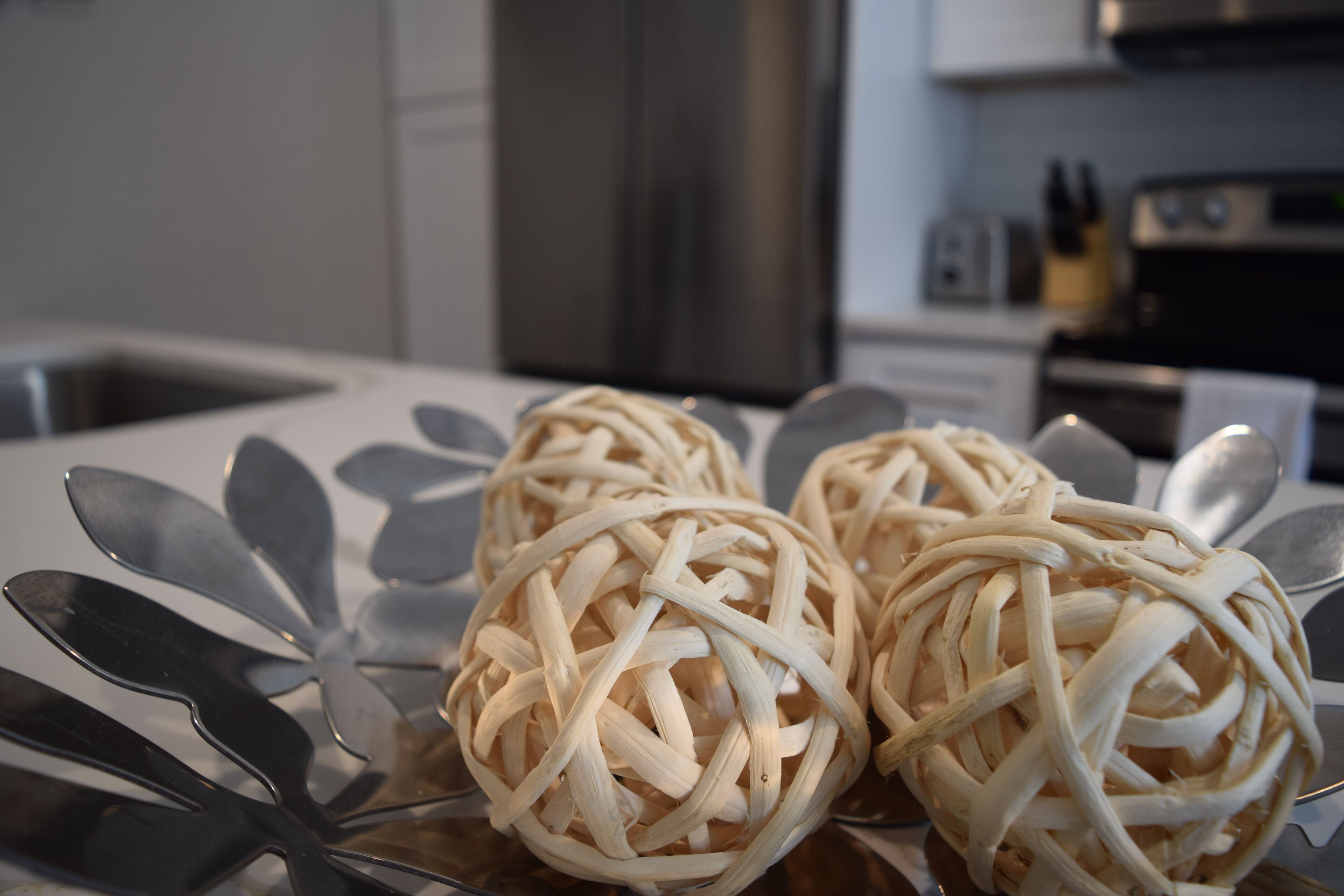 Three woven balls on a table with a metallic spoon in the foreground.