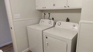 A laundry area with two white front-loading washing machines and a cabinet above them.