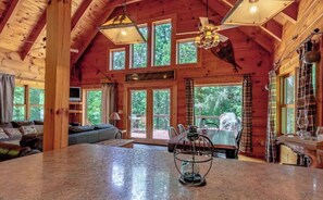 Spacious room with high ceilings and exposed beams, featuring a large granite countertop, dining area, and seating area with sofa.