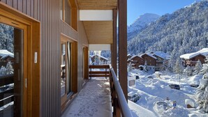 A wooden balcony with a view of a snowy mountain resort. - Sherpa 17 spacious apartment with sauna (Les Allues)