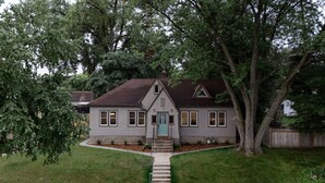 A two-story house with a front porch, a visible front door, and a small front yard with a pathway leading to the door. - Quiet and Modern Designed Cottage in St Paul (St. Paul)