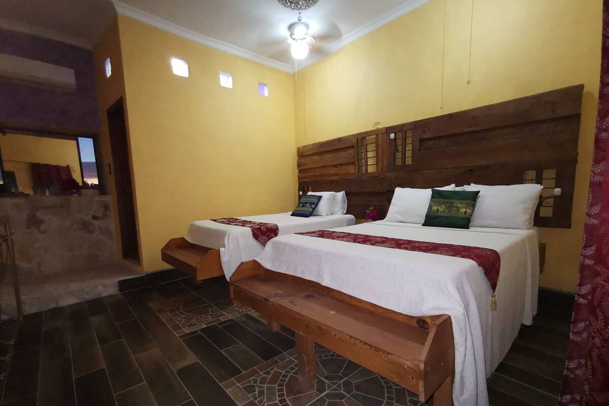 A room with two beds, a wooden bench, and a tiled floor.