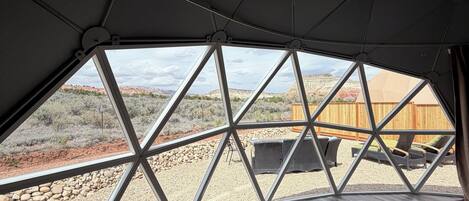 Una habitación con un diseño geométrico en el techo, vistas a un paisaje desértico y suelo de madera.