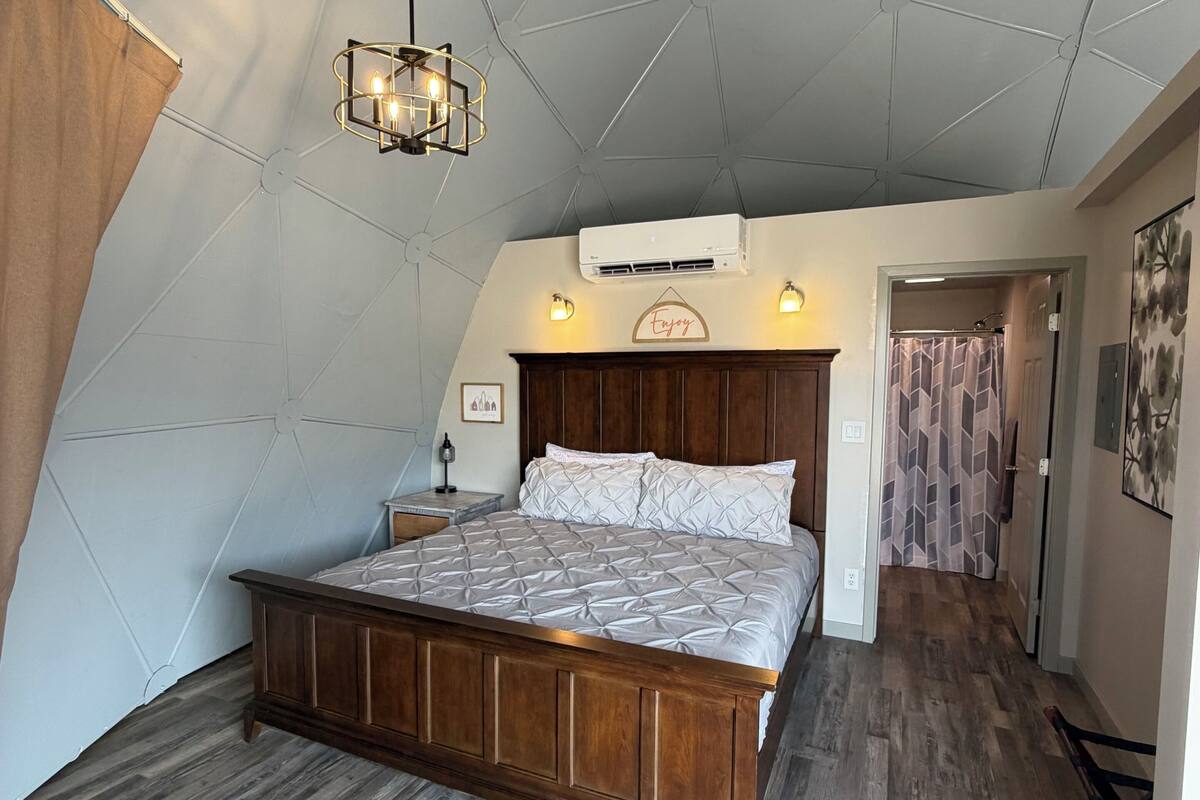Une chambre à coucher avec un lit en bois, un luminaire suspendu et un appareil de climatisation.