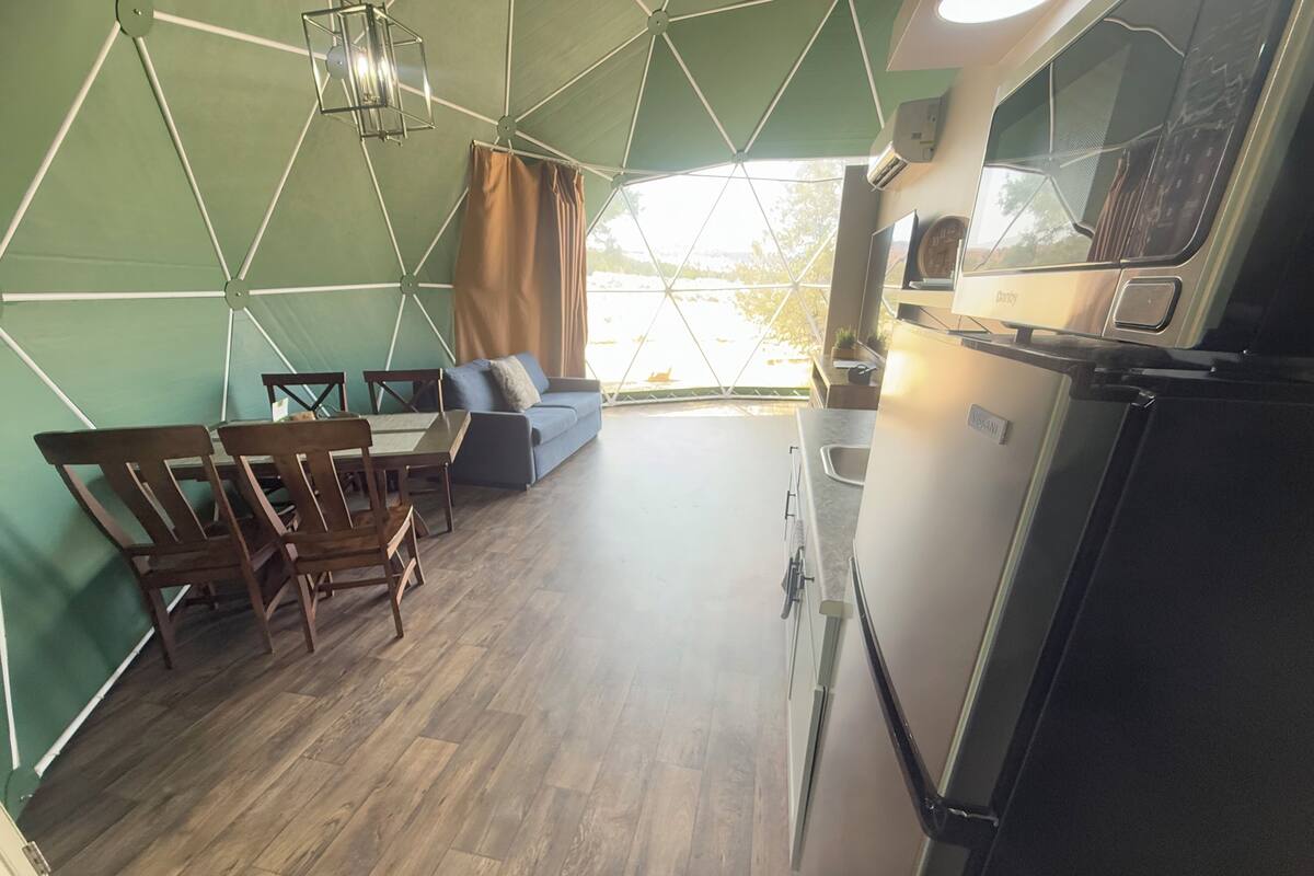 Une cuisine moderne équipée d’un réfrigérateur, d’un évier et d’un coin repas avec des chaises et une table en bois.
