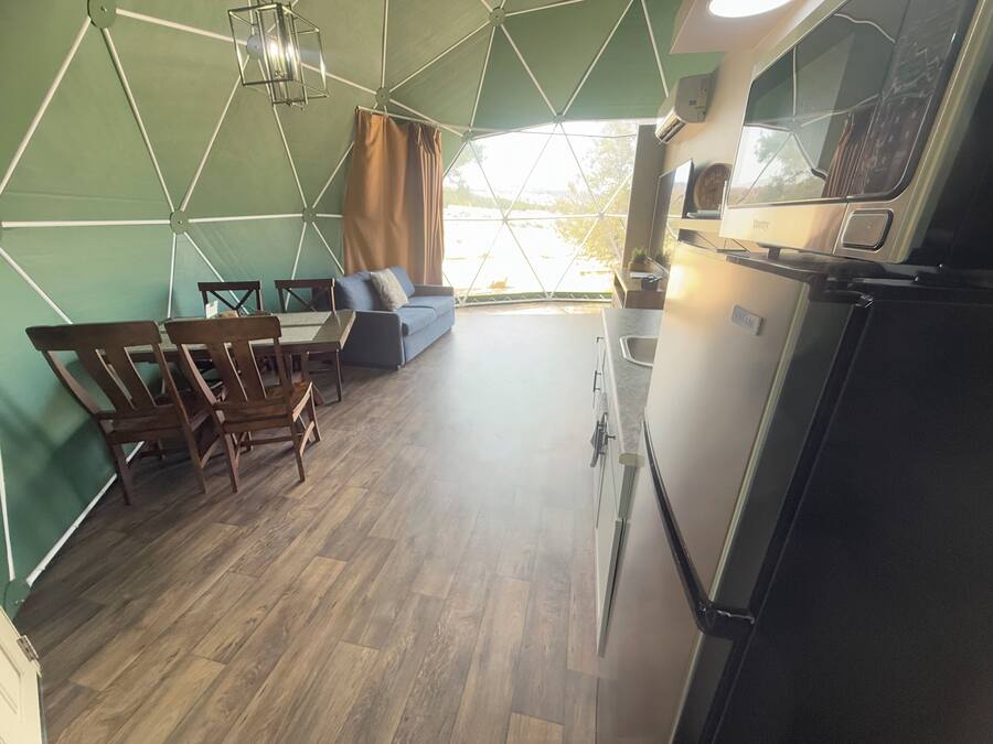 A modern kitchen with a refrigerator, sink, and dining area with wooden chairs and a table.
