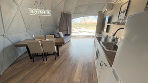 Een moderne keuken met een eethoek, met een geometrisch plafondontwerp, houten vloeren en uitzicht op de omgeving.
