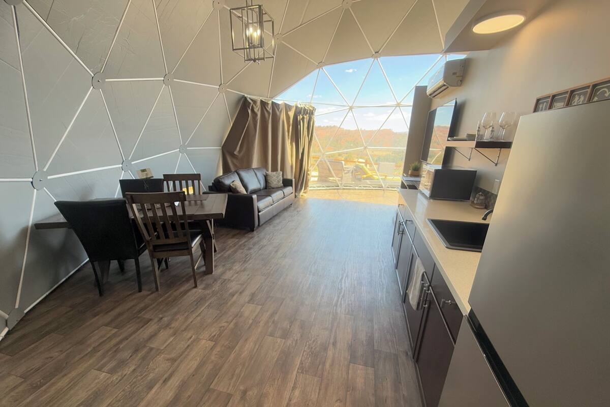 Un espace de vie moderne, ouvert et décloisonné, comprenant un coin repas, un canapé et une cuisine.