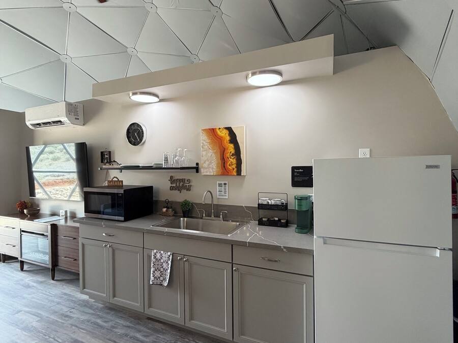 Cozinha moderna com ilha central, forno embutido, geladeira e ventilador de teto.