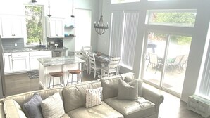 A spacious living area with a large sectional sofa, a dining table, and a kitchen in the background. - Gorgeous lake house with sandy beachfront. Welcome to Lost  World Landing  (Eufaula)