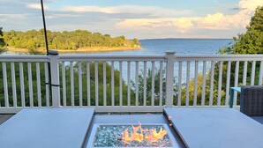 A deck with a fire feature, white railings, and a view of a lake and forest. - Gorgeous lake house with sandy beachfront. Welcome to Lost  World Landing  (Eufaula)