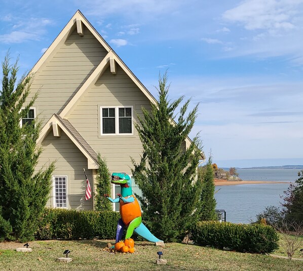 Ein Haus mit Satteldach, einer Flagge und einer Dinosaurierstatue im Vorgarten.