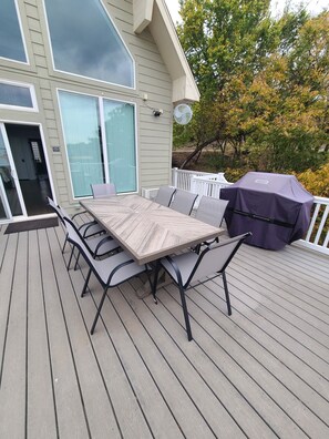 Eine Terrasse mit Tisch, Stühlen, einem Grill und einem Haus im Hintergrund.