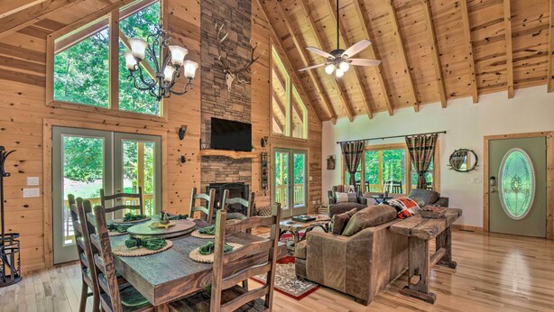 A spacious wooden cabin with a dining area, a fireplace, a large window, and a cozy living room. - Great for Families! Lavish Hiawassee Cabin (Hiawassee)