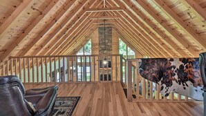 A spacious attic room with wooden beams, a stone fireplace, and a cowhide rug. - Great for Families! Lavish Hiawassee Cabin (Hiawassee)
