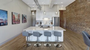 Una cocina moderna con una isla central, taburetes de bar y lámparas colgantes.
