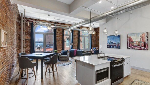 Una cocina moderna con una isla central, una zona de comedor con sillas y un rincón de estar con sofás.