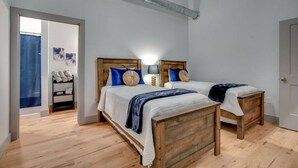 Un dormitorio con dos camas de madera, un ventilador de techo y una puerta de baño visible.