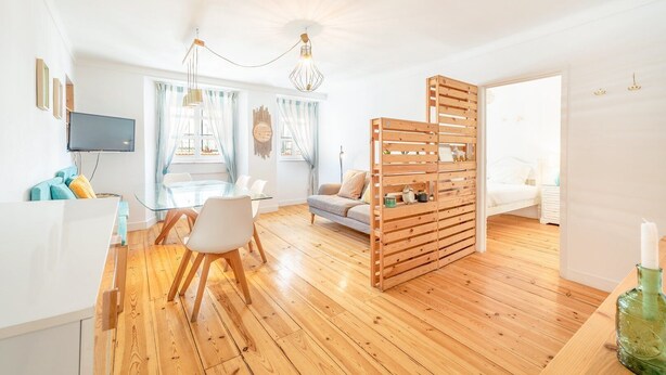 Ein modernes Wohnzimmer mit einem Glastisch, Holzboden und einer Holzwand mit Regalen.