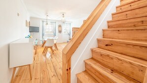 Eine Holztreppe führt zu einem Essbereich mit Tisch und Stühlen.